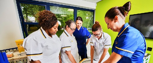 A group of nursing students attending to a mock patient.