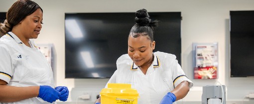 Two nursing students attending to a mock patient.