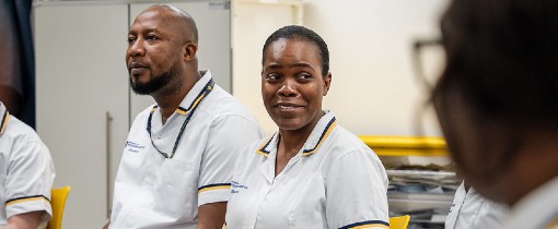 Image of a group of Adult Nursing students in medical clothing sitting together.