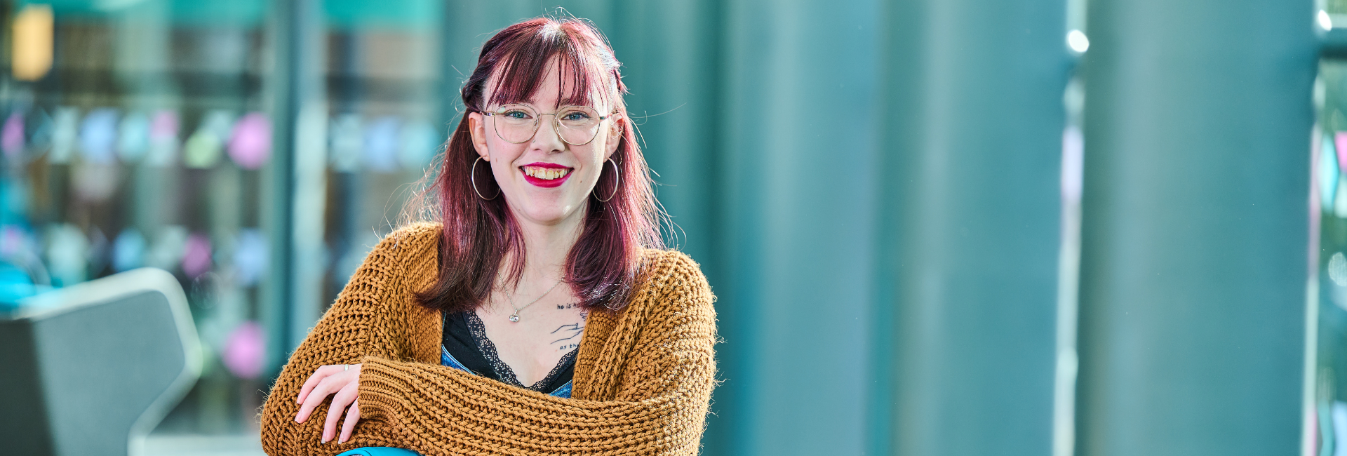 A picture of a student smiling into the camera, wearing a yellow cardigan