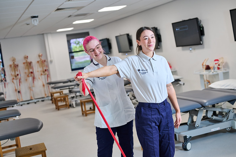 Two students in the nursing classroom demonstrating restrictive band movements.
