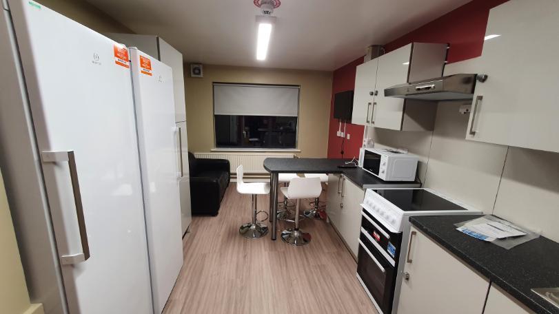 Kitchen from Telford Campus accommodation, with fridge/freezers facing the countertop and a seating area with a television at the far end of the room