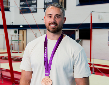 Kristian Thomas photographed wearing a white shirt and an Olympic bronze medal.