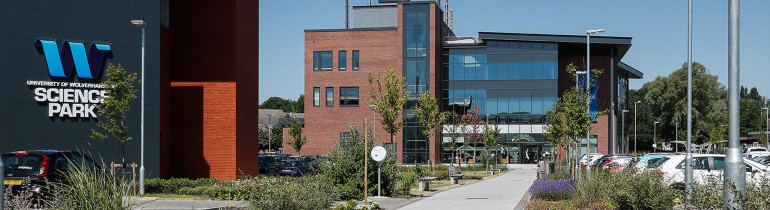 Exterior of the Science Park, with parking areas and greenery along a path leading to the entrance, the University of Wolverhampton Science Park signage on a wall of the building