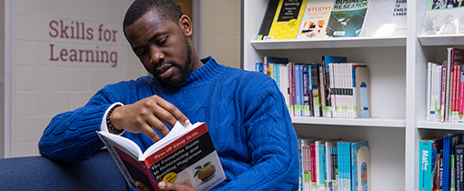 student reading academic skills book in Library