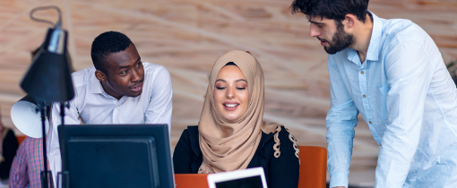 Three people stood around a computer screen on a tabletop.