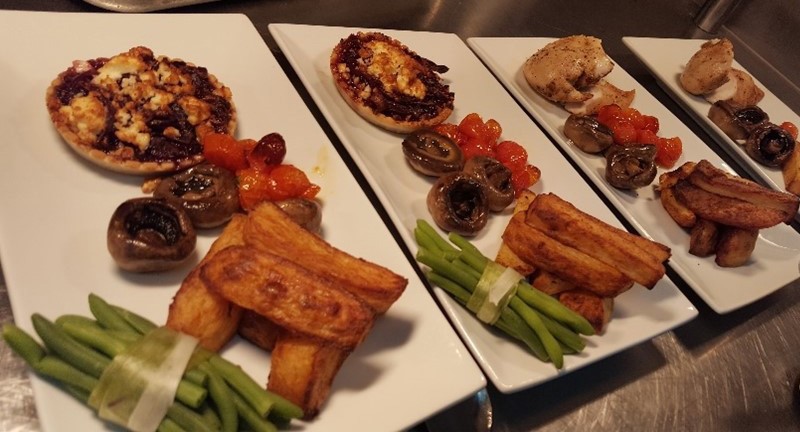 Multiple hot cooked meals prepared to be served sitting on a kitchen surface.