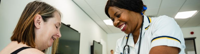A nursing student in nursing uniform checking a patient's blood pressure