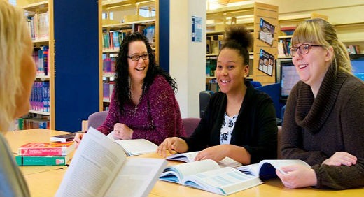 Four PhD students sitting at a table and reading