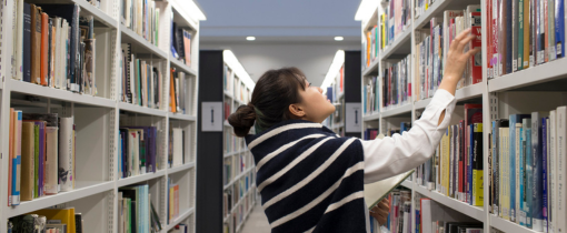 a female student chooses a book in a library