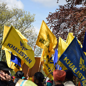 Photograph of a Khalistan movement gathering, crowds of people carrying yellow and blue flags.