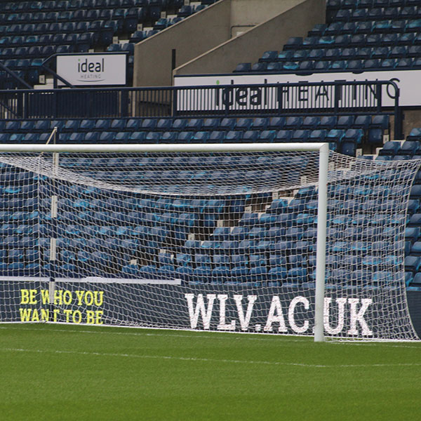 Photograph by Benedict Ferraby of a goal on a football pitch, an advertisement for the University of Wolverhampton website displayed behind it