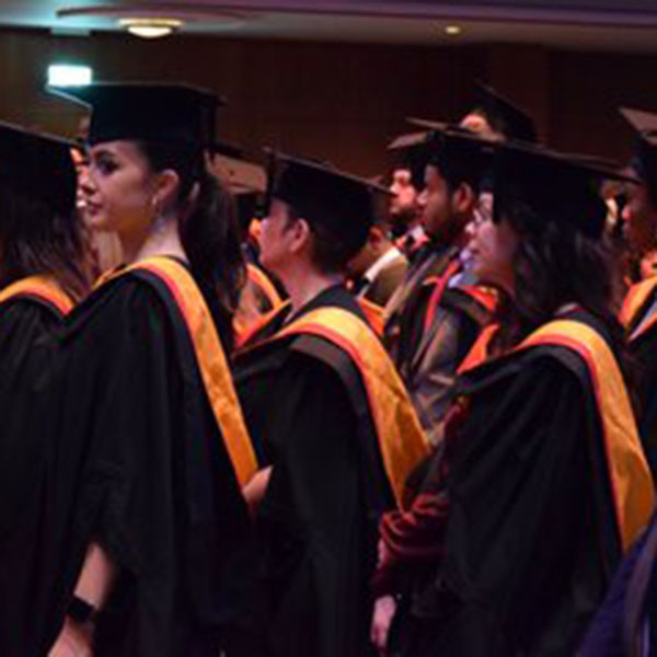 Photo of University of Wolverhampton graduates stood in a line, wearing their undergraduate robes