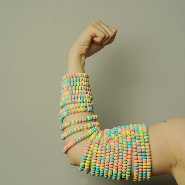 Photograph of a flexing arm wrapped in candy bracelets.