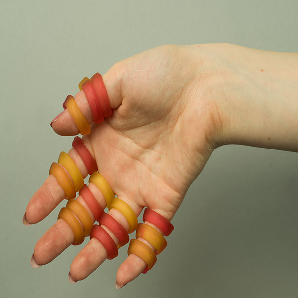 Photograph of a hand whose fingers are wrapped with gummy rings.