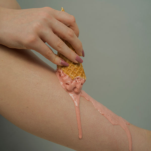Photograph of a pink ice-cream melting across a leg.