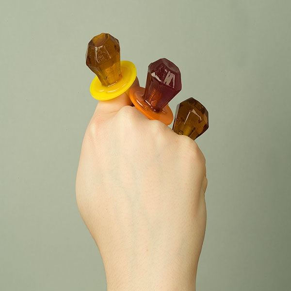 A closed fist clutching three candy rings.