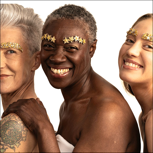 Three people photographed together, their eyebrows decorated with thick glitter, sequins and stars.