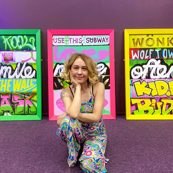 Keri Hunt posed in front of three of her framed artworks.