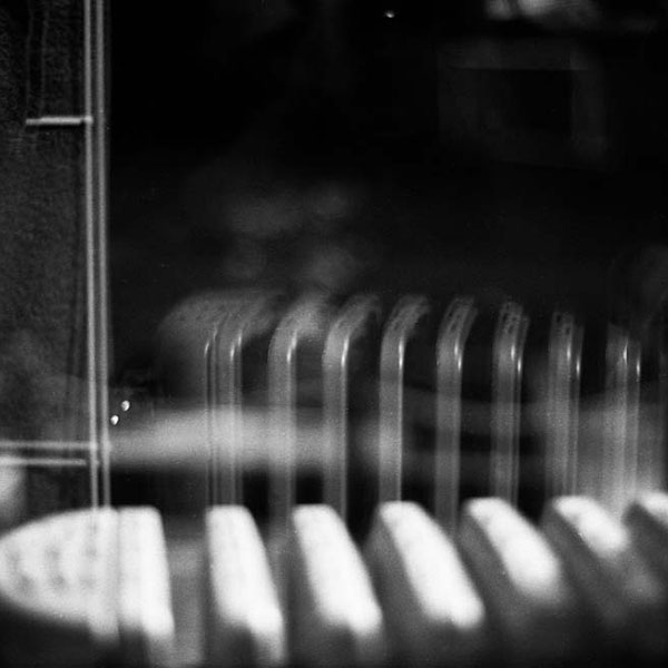 Black and white photograph of a radiator reflected in a pane of glass.