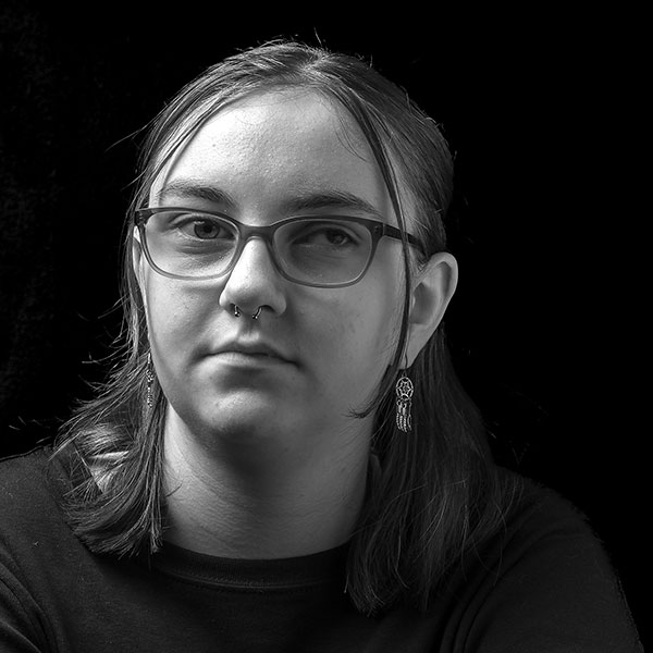 Black and white portrait photograph of a young woman wearing glasses.