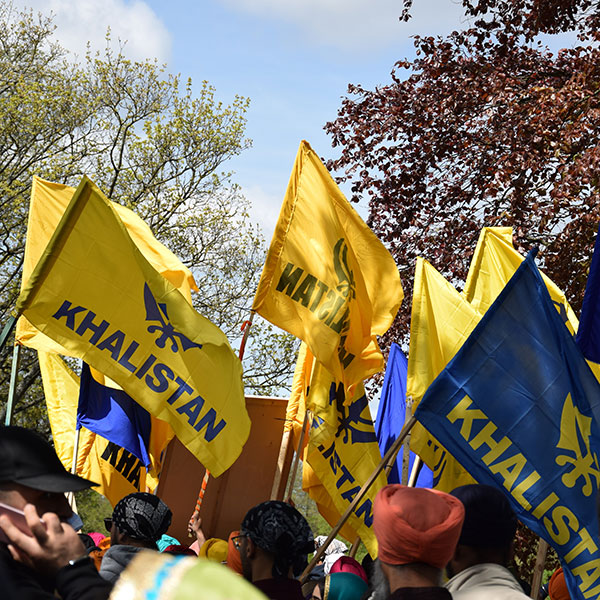 Photograph of a Khalistan movement gathering, crowds of people carrying yellow and blue flags.