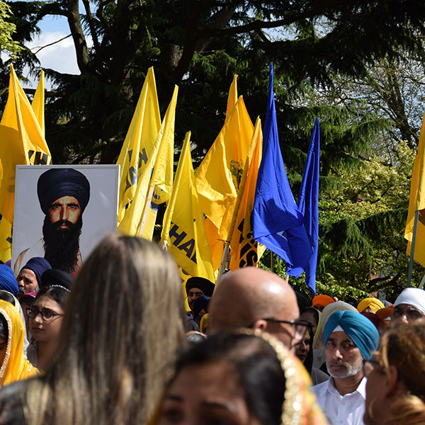Photograph taken at a Khalistan movement gathering, with yellow flags fling and large photographs of prominent movement figures.