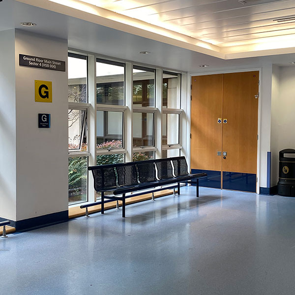 Photograph of a black metal bench inside the ground floor lobby of a large building.