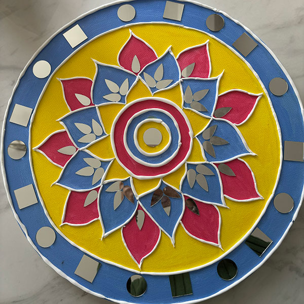 A round surface with a flower pattern constructed at its centre using blue, yellow and red petal shapes.