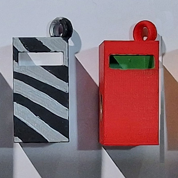An array of variously painted and patterned cuboid boxes, each with a post-box slit cut out of their upper sections, a circular hole on their sides and a ring stuck to their tops.