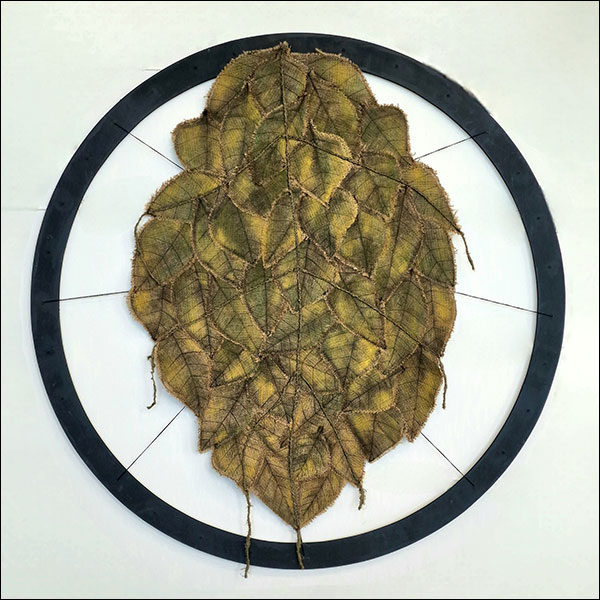 A leaf shape comprised of several collaged individual leaves, held together inside a black circle.