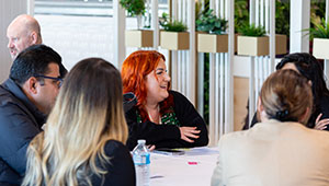 Laura May Jennings from the Disability Resource Centre. Laura is pictured sat in the middle of a group meeting. She has long red hair and is wearing a black long sleeved top