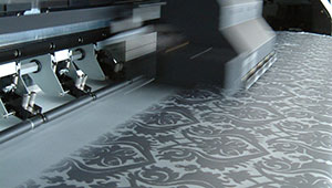 Close up of the large textiles printer. In this image you can see a blue floral pattern being printed onto white paper.