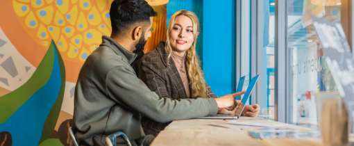 Interior of Springfield Campus showing a first floor computer lab with a glass roof and stairs leading down towards the building entrance, a play button identifying this as a video link