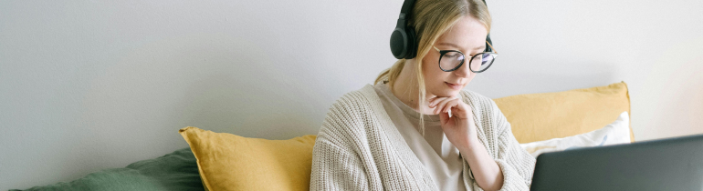 A student wearing headphones looking at a laptop screen