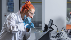 A student holding a tyre next to a racing car.