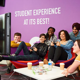 image of a group of students sitting watching 2 others play on a games console