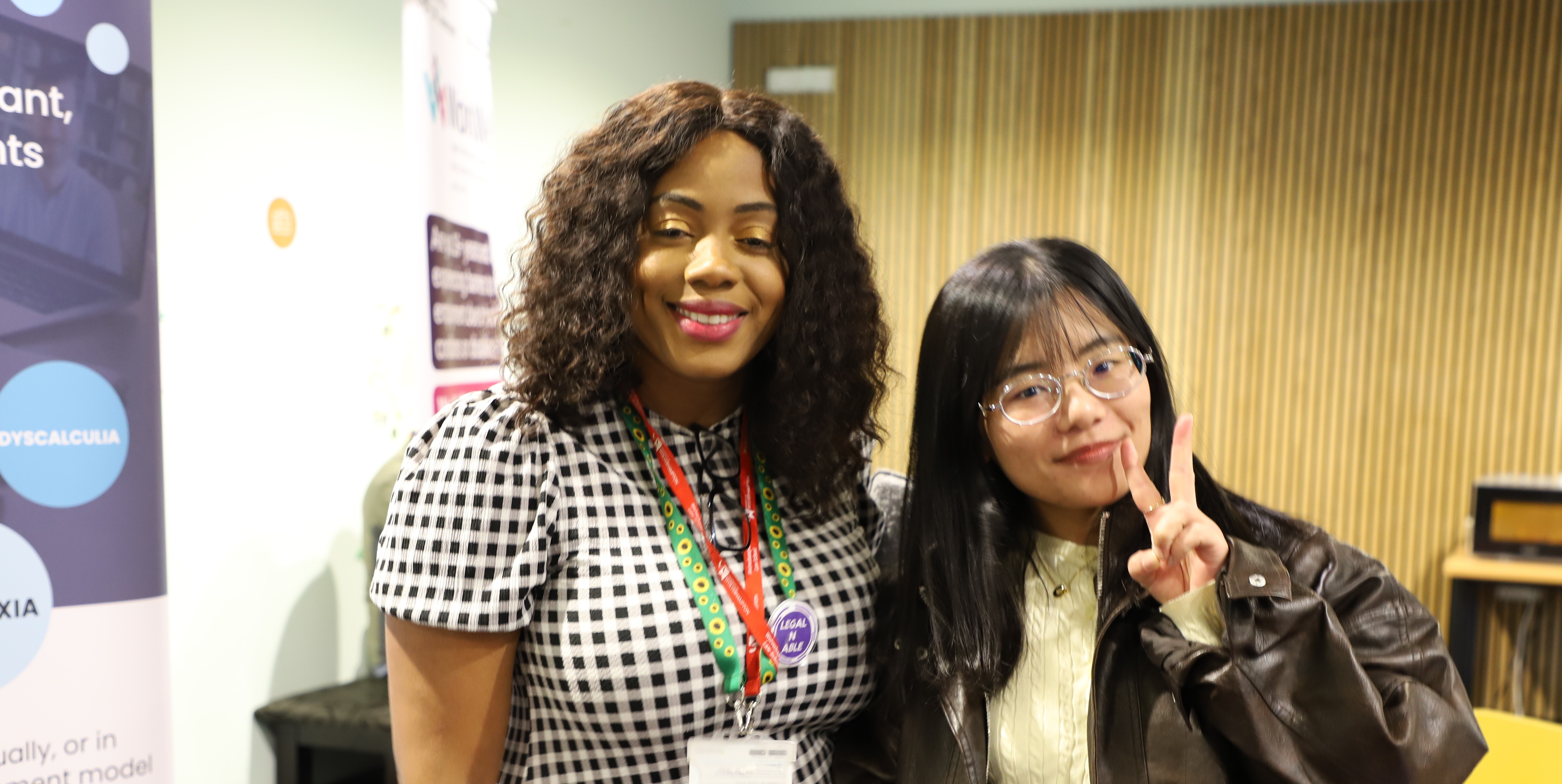 Two female students smiling, one is doing the peace sign