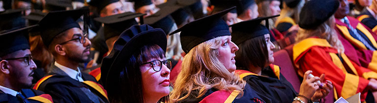 Photograph of students and academics wearing robes while seated for a graduation ceremony.