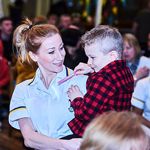 Nursing student holding child at Nursing Badge Ceremony