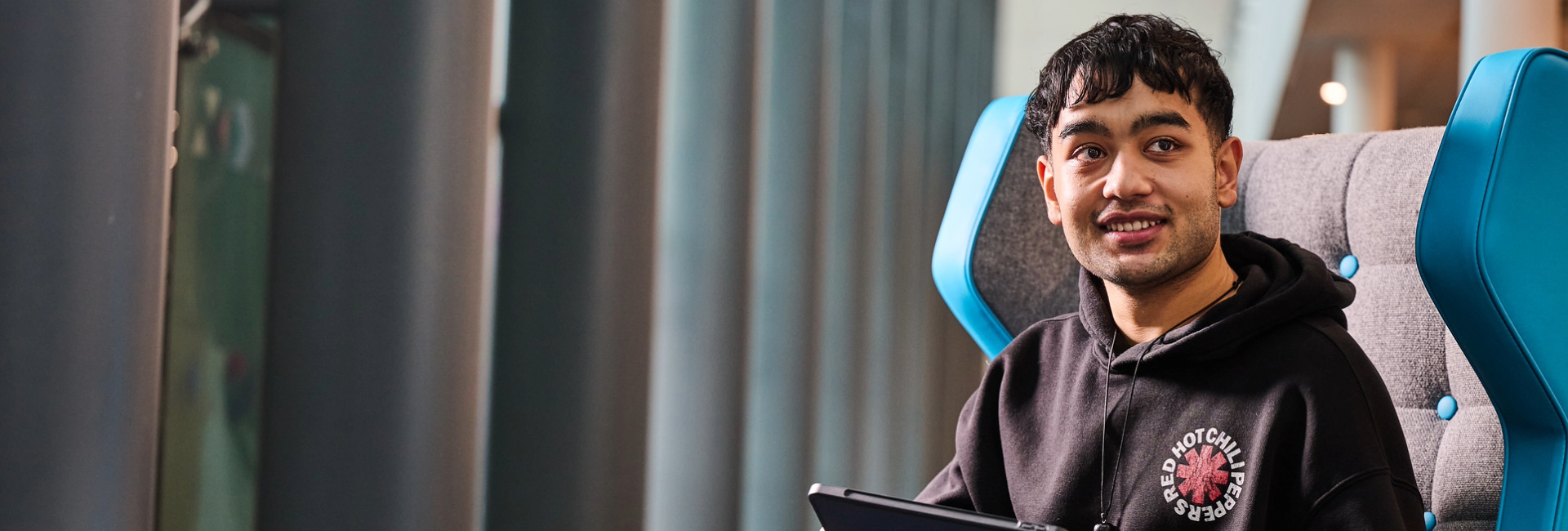 Student sat in chair holding laptop