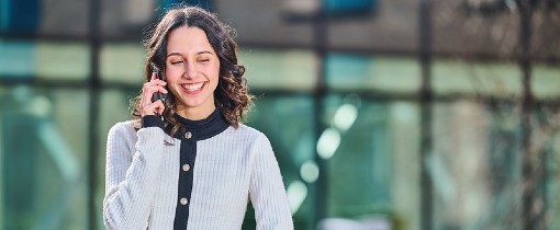A student resting her arm on a handrail, speaking on her mobile phone.