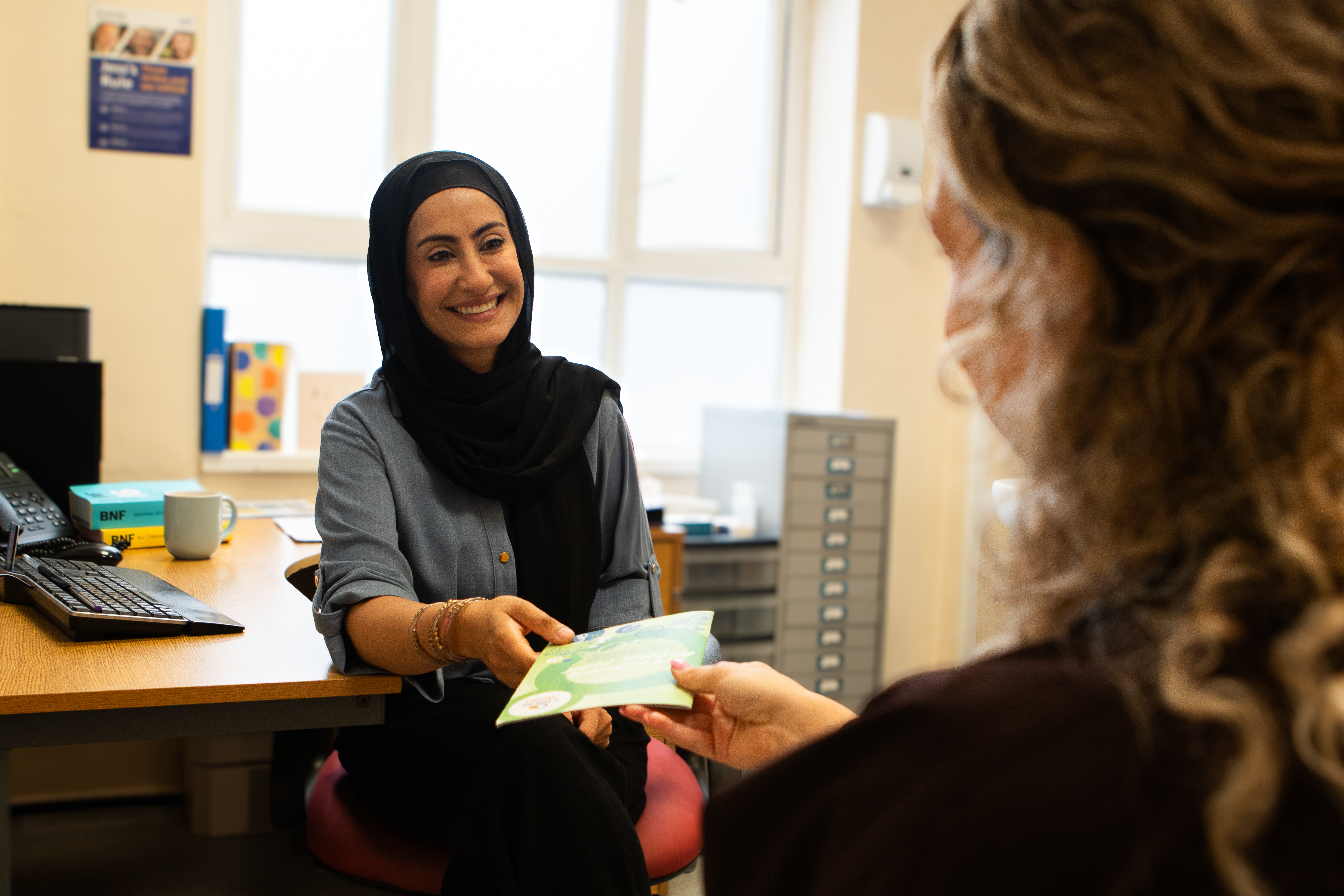 A woman consulting another person behind a desk