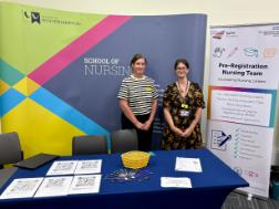 Two students smiling at camera standing at stand