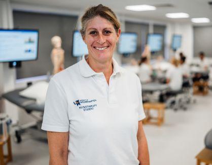 Student Vanessa smiling at camera in uniform and in clinic