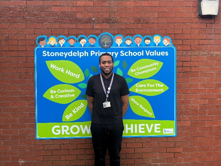 Student Jonathan standing by a wall smiling