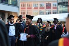 Students in graduation gowns smiling at camera