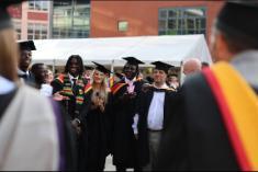 Students in graduation gowns smiling at camera