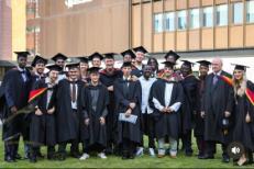 Students in graduation gowns smiling at camera