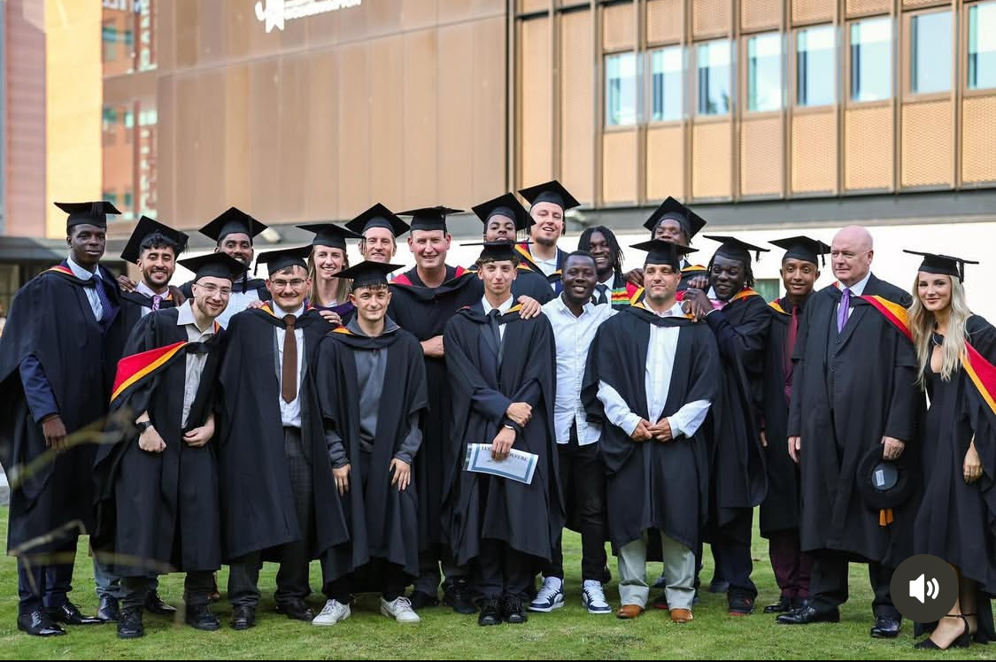 Students in graduation gowns smiling at camera